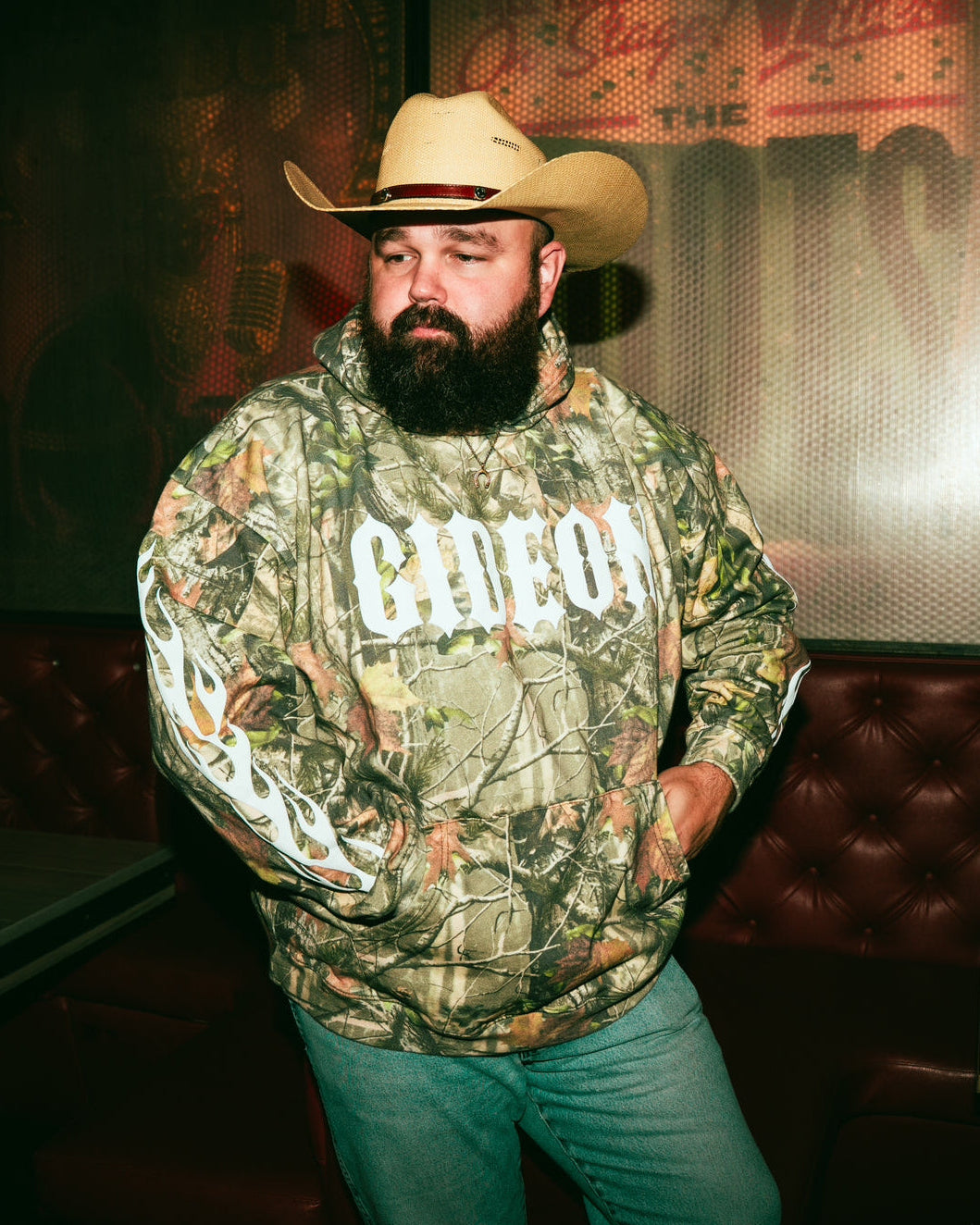 Daniel McWhorter wearing a camouflage hoodie with 'Gideon' text and flame print sleeves.