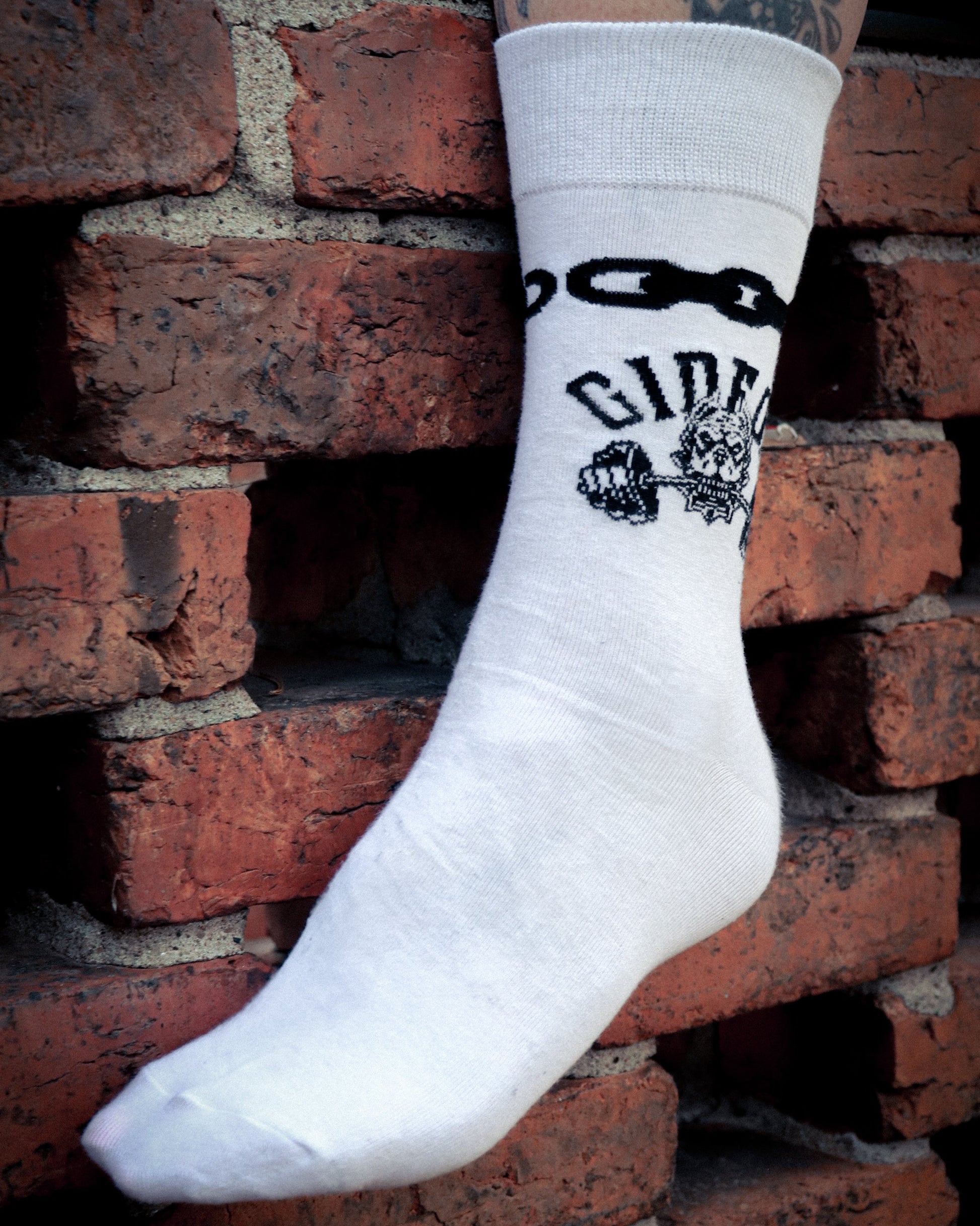 Gideon band merchandise. White sock, quarter crew length. Black chain link around top and on side outer a dog biting down on barbell.