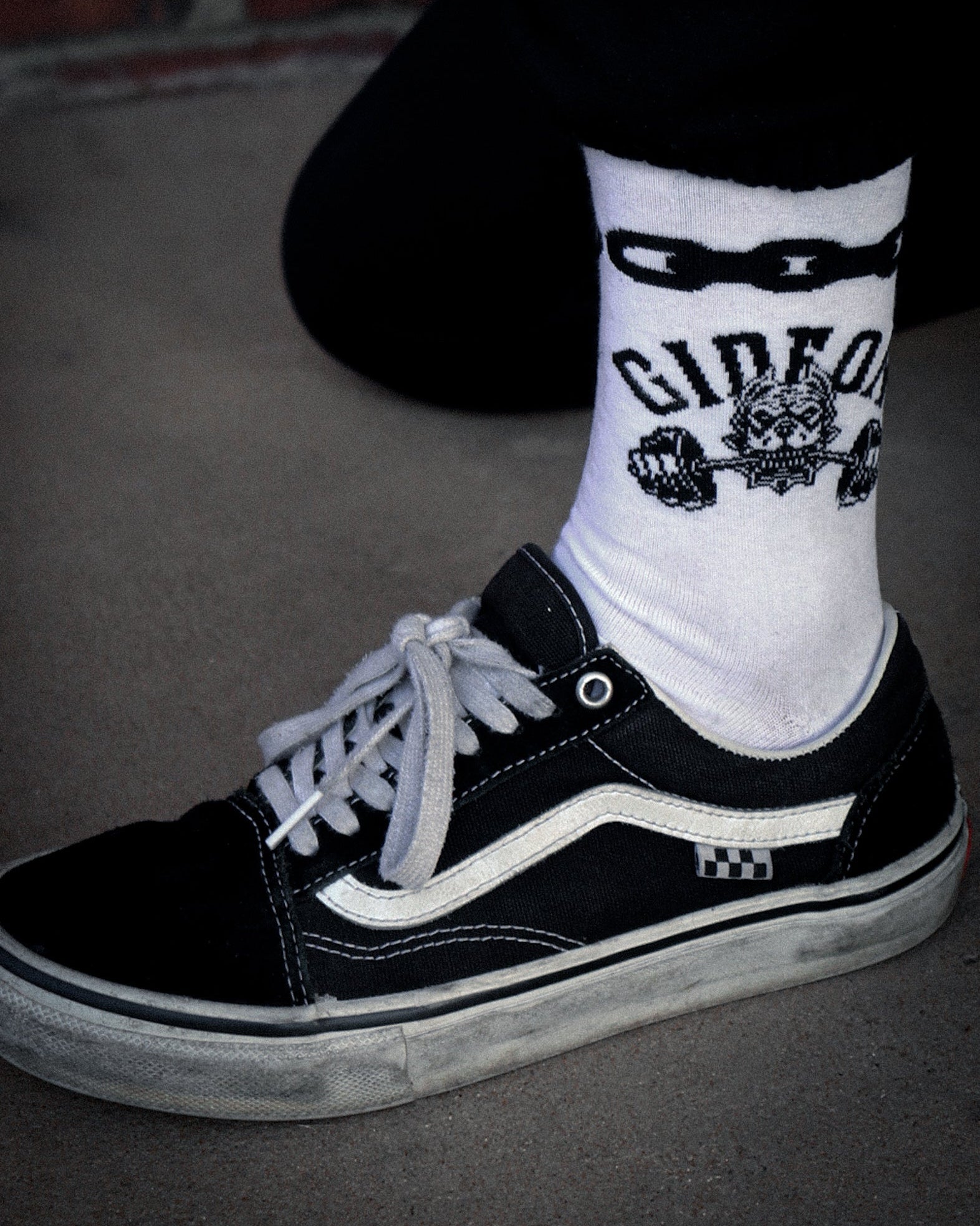 Gideon band merchandise. White sock, quarter crew length. Black chain link around top and on left side a dog biting down on barbell.